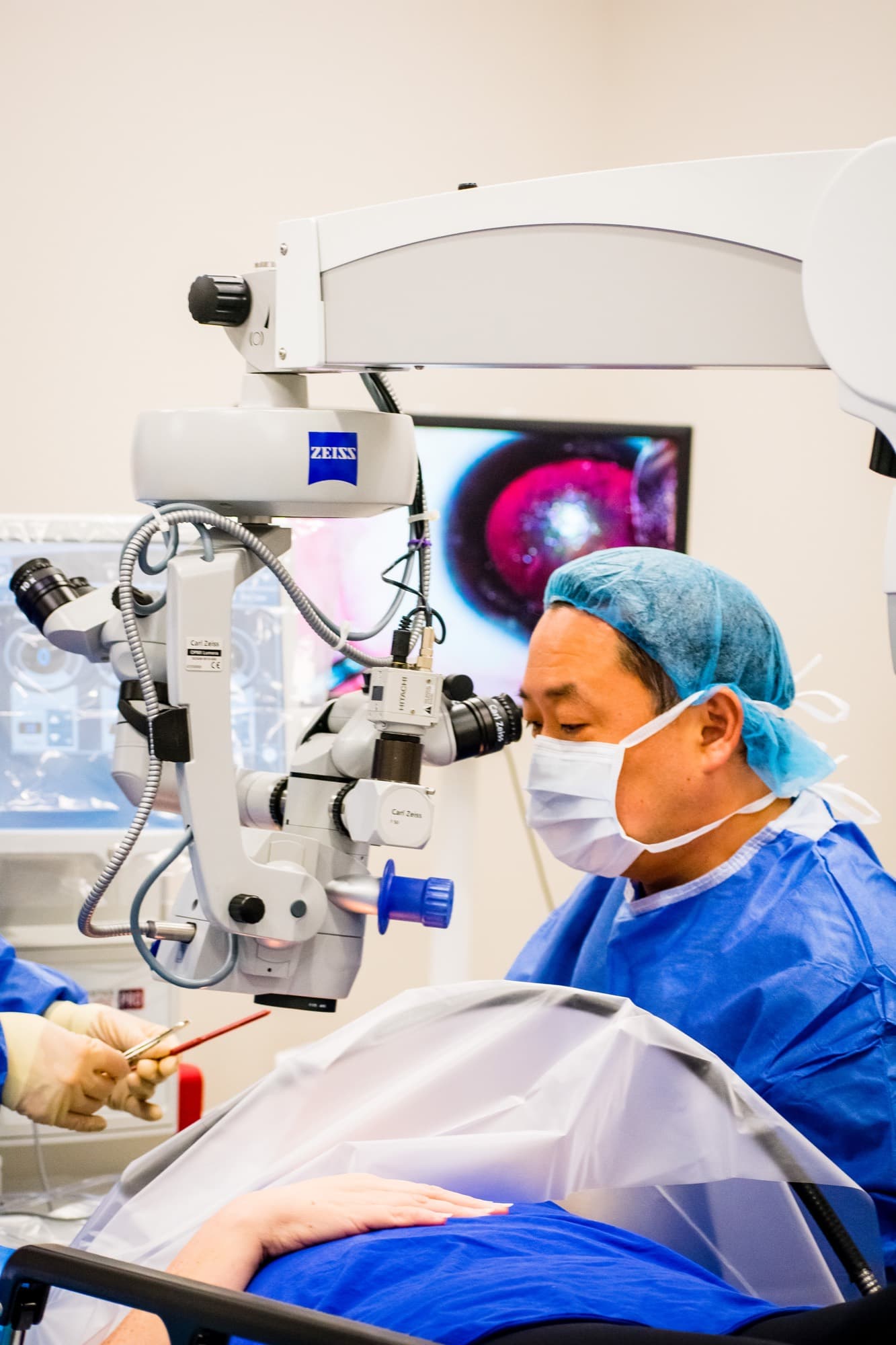 A Texas Vision surgeon at the operating microscope, the eye visible on the surgical monitor